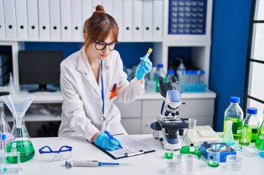 Laboratuvarda test tüpü tutan genç bilim kadını.