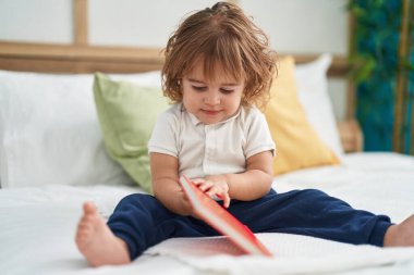 Sevimli İspanyol bebek kitap okuyor. Yatak odasında oturuyor.