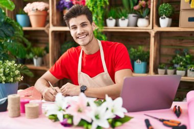 Çiçekçide dizüstü bilgisayar kullanan İspanyol bir çiçekçi.