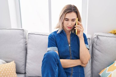 Evde akıllı telefondan konuşan genç bir kadın.
