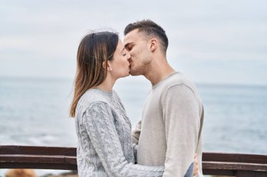 Man and woman couple hugging each other kissing at seaside