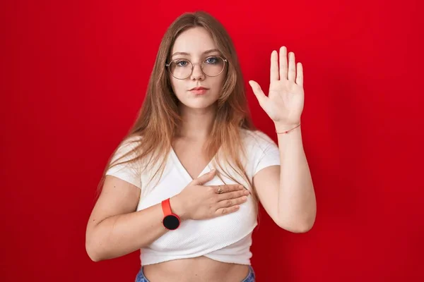 Young Caucasian Woman Standing Red Background Swearing Hand Chest Open — 图库照片