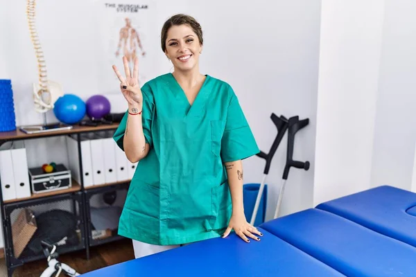 Jeune Femme Hispanique Portant Uniforme Physiothérapeute Debout Clinique Montrant Pointant — Photo