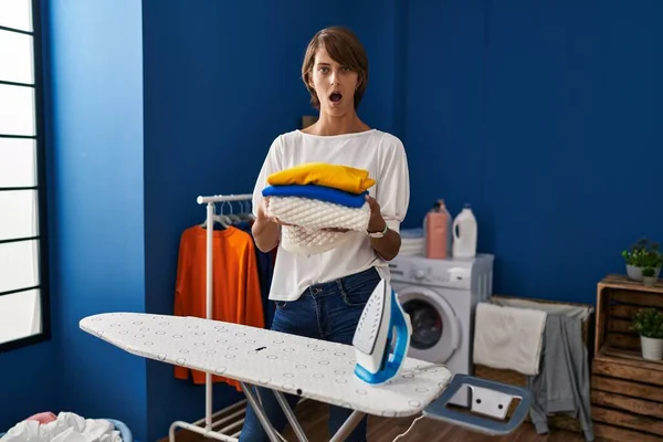 Brunette Woman Holding Folded Laundry Ironing Afraid Shocked Surprise Amazed — ストック写真