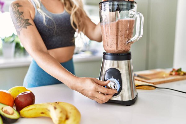 Young woman blending healthy smoothie at kitchen