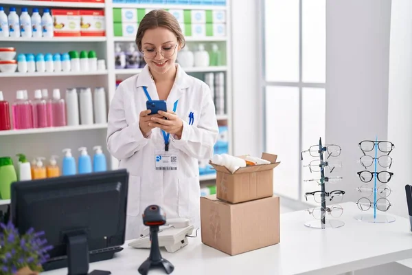 Young Blonde Woman Pharmacist Using Smartphone Working Pharmacy — Zdjęcie stockowe