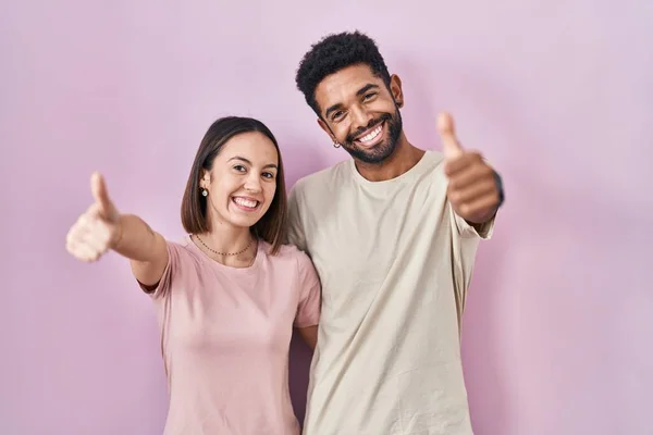 Young Hispanic Couple Together Pink Background Approving Doing Positive Gesture — Stockfoto