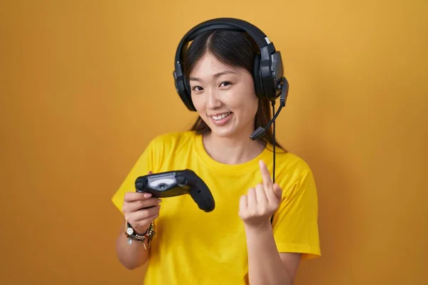 中国の若いです女性プレイビデオゲームホールディングコントローラ手招きここに来てジェスチャーで手を歓迎幸せと笑顔 — ストック写真