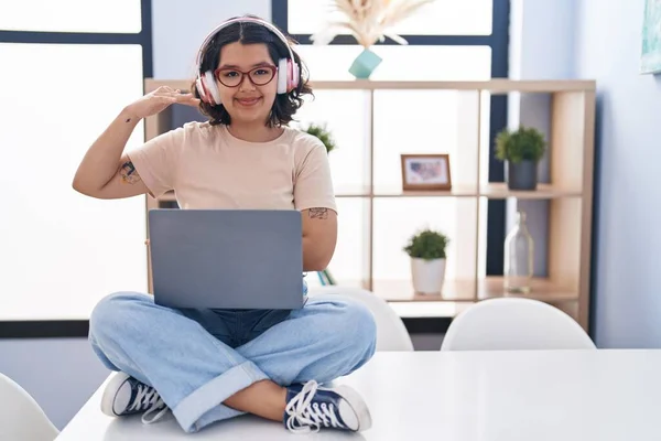 Young Hispanic Woman Using Laptop Sitting Table Wearing Headphones Gesturing —  Fotos de Stock