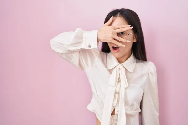 Молодая Китаянка Стоящая Розовом Фоне Заглядывая Рукой Лицо Глаза Смотрит — стоковое фото