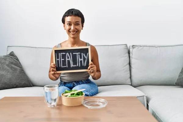 Young Hispanic Woman Eating Salad Holding Healthy Blackboard Home — Stockfoto