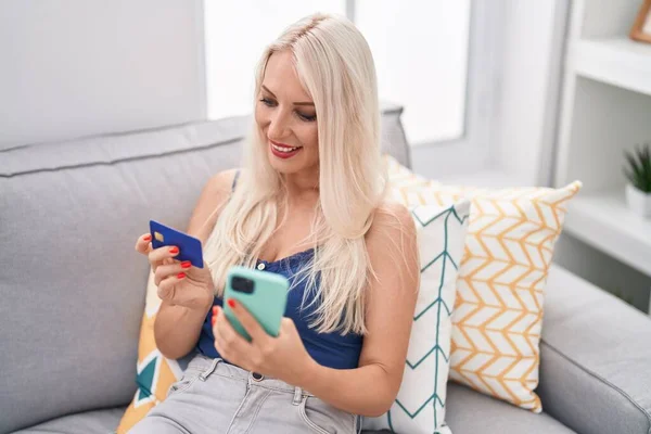 Ung Blond Kvinna Som Använder Smartphone Och Kreditkort Sitter Soffan — Stockfoto
