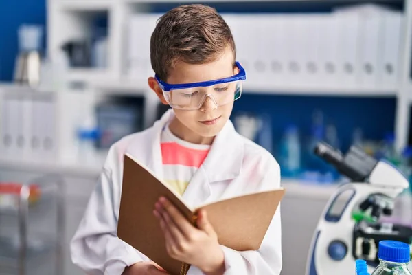 实验室里穿着科学家制服的金发孩子看书 — 图库照片