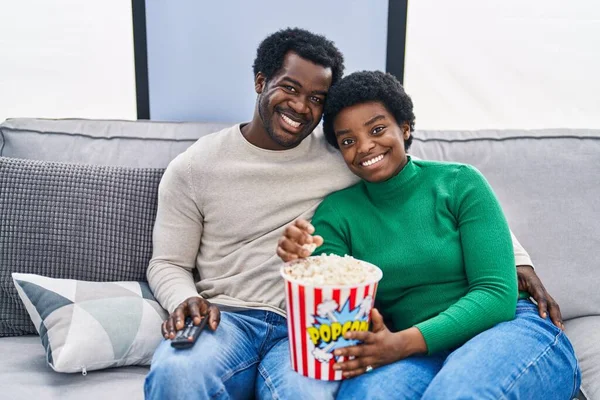 stock image African american man and woman couple watching movie eating popcorn at home