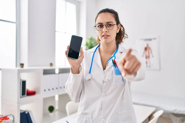 Young Hispanic Doctor Woman Holding Smartphone Showing Screen Pointing Finger — Stock Photo, Image