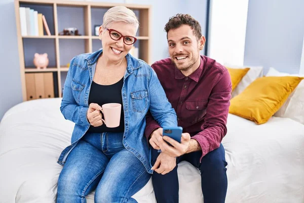 Mother Son Using Smartphone Drinking Coffee Sitting Bed Bedroom — Stockfoto