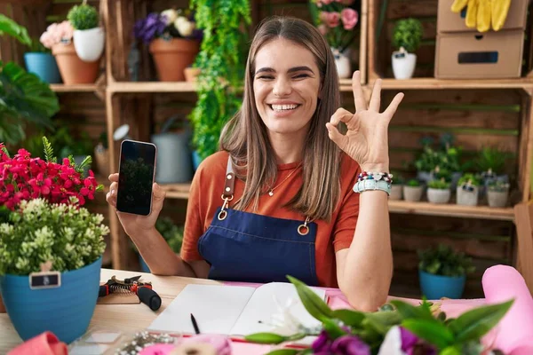 Hispanic Young Woman Working Florist Shop Showing Smartphone Screen Doing — Zdjęcie stockowe