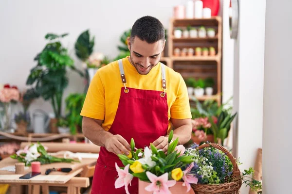 Young hispanic man florist smiling confident touching flowers at florist