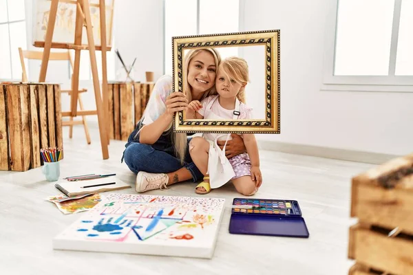 Mother Daughter Smiling Confident Holding Empty Frame Sitting Floor Art — Stok fotoğraf