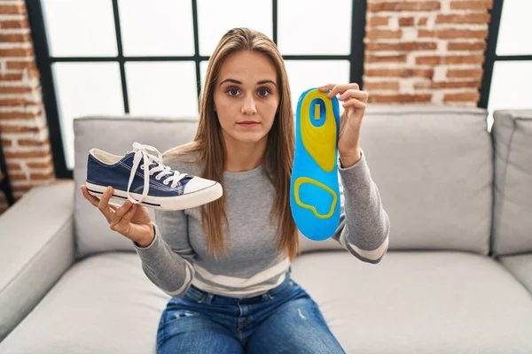 Young woman holding shoe insole skeptic and nervous, frowning upset because of problem. negative person.