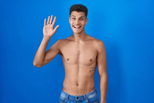 Young Hispanic Man Standing Shirtless Blue Background Waiving Saying Hello — Fotografia de Stock