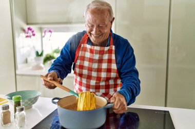 Son sınıf öğrencisi, mutfakta spagetti pişirme konusunda kendinden emin gülümsüyor.
