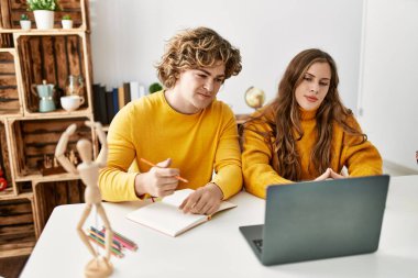 Genç beyaz çift evde online resim dersi aldıklarından emin gülümsüyor.