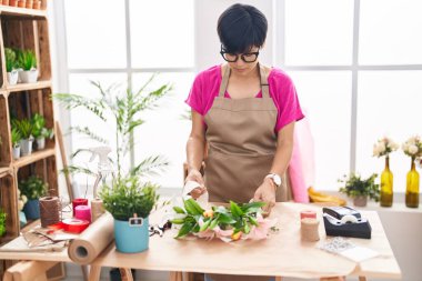 Middle age chinese woman florist make bouquet of flowers at flower shop