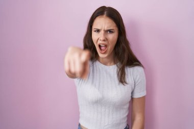 Young hispanic girl standing over pink background pointing displeased and frustrated to the camera, angry and furious with you 