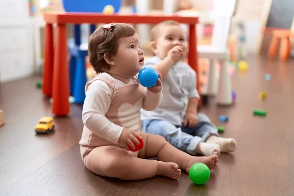 幼稚園の床に座ってボールで遊んでいる2人の幼児 — ストック写真