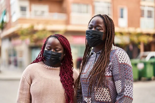 African american women friends wearing mask standing together at street