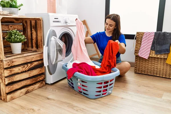 在洗衣房用洗衣机清洁衣服的年轻高加索女人 — 图库照片