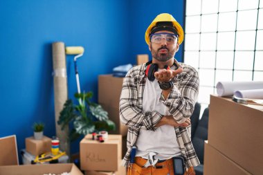 Sakallı, ev tadilatında çalışan genç İspanyol bir adam kameraya bakıp havada öpüşüyor ve güzel ve seksi oluyor. aşk ifadesi. 