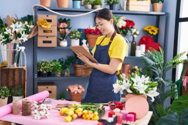 Chinese woman florist smiling confident writing on document at florist shop