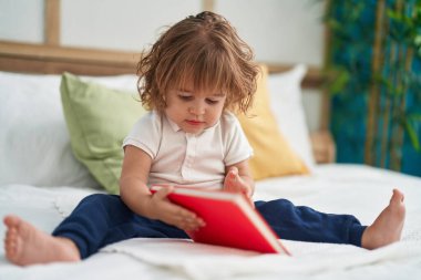 Sevimli İspanyol bebek kitap okuyor. Yatak odasında oturuyor.