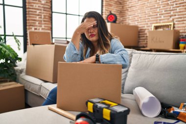 Young beautiful plus size woman stressed sitting on sofa at new home