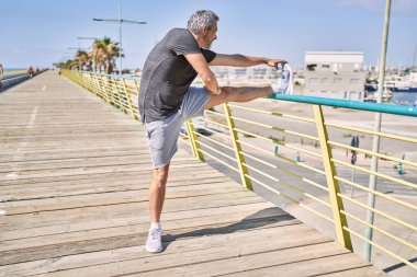 Orta yaşlı İspanyol adam spor giyer, sokakta esniyor.