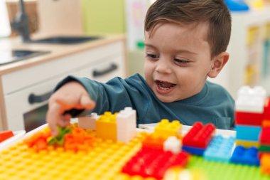 Anaokulundaki masada oturan, inşaat bloklarıyla oynayan sevimli İspanyol çocuk.