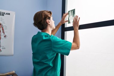 Young caucasian man physiotherapist looking xray on window at rehab clinic