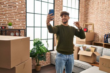 Young arab man make selfie by smartphone holding key at new home