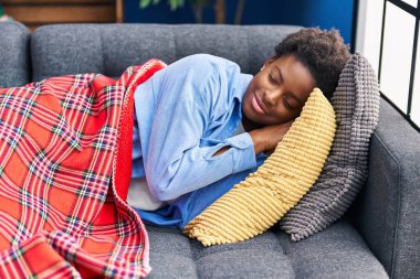 African american woman lying on sofa sleeping at home