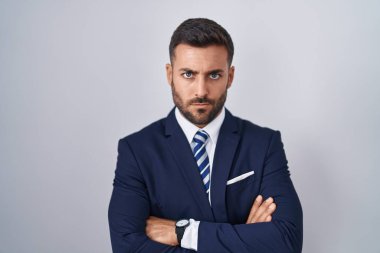 Handsome hispanic man wearing suit and tie skeptic and nervous, disapproving expression on face with crossed arms. negative person. 