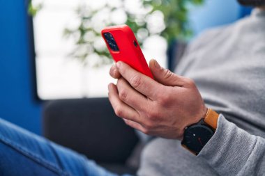 Young latin man using smartphone at home