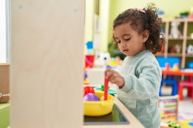 Sevimli İspanyol kız kreşte mutfakta oyun oynuyor.