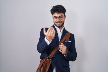 Hispanic man with beard wearing business clothes beckoning come here gesture with hand inviting welcoming happy and smiling 