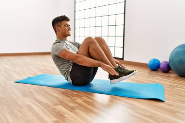 Genç İspanyol adam gülümsüyor spor merkezinde kendine güvenen karın kasları egzersizi yapıyor.