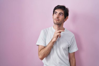 Pembe arka planda duran Latin kökenli genç adam parmak çenesinde şüpheye yoğunlaşmıştı. 