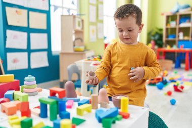 Adorable caucasian boy playing with toys sitting on floor at kindergarten