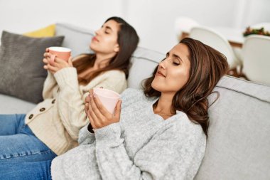 Evde kahve içen kendine güvenen iki kadın.