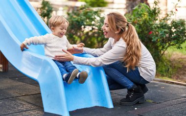 Mother and son playing on slide at park